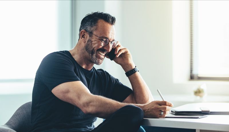 Happy man sitting at desk working after testosterone therapy.