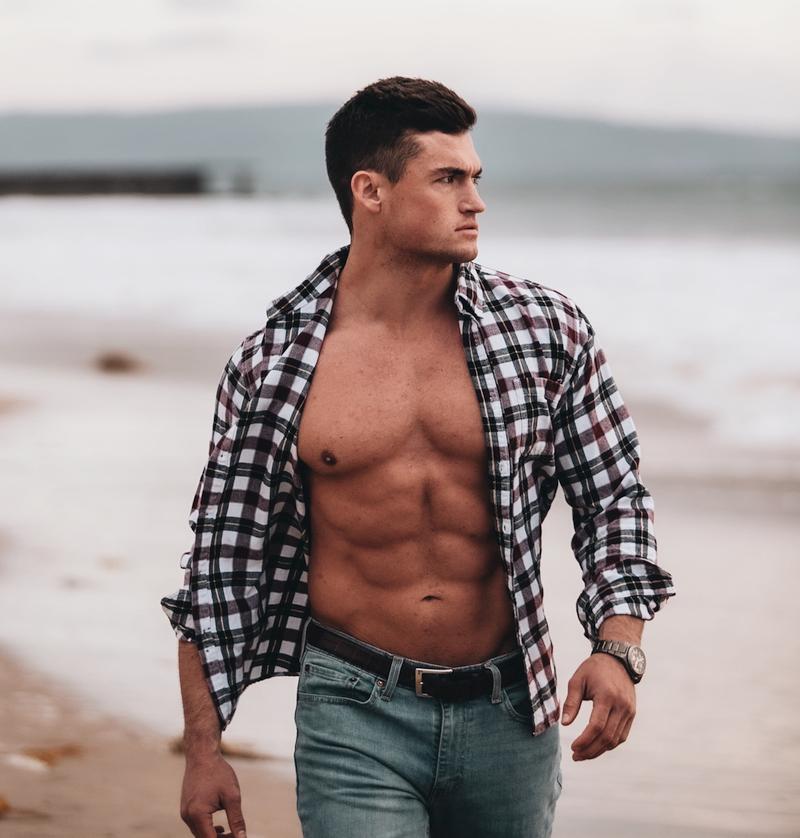Healthy muscular man walking down the beach